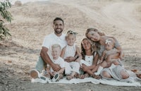 a family sits on a blanket in a dirt field