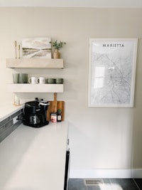 a white kitchen with a coffee maker and a map