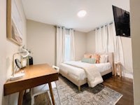 a bedroom with a bed, desk and tv